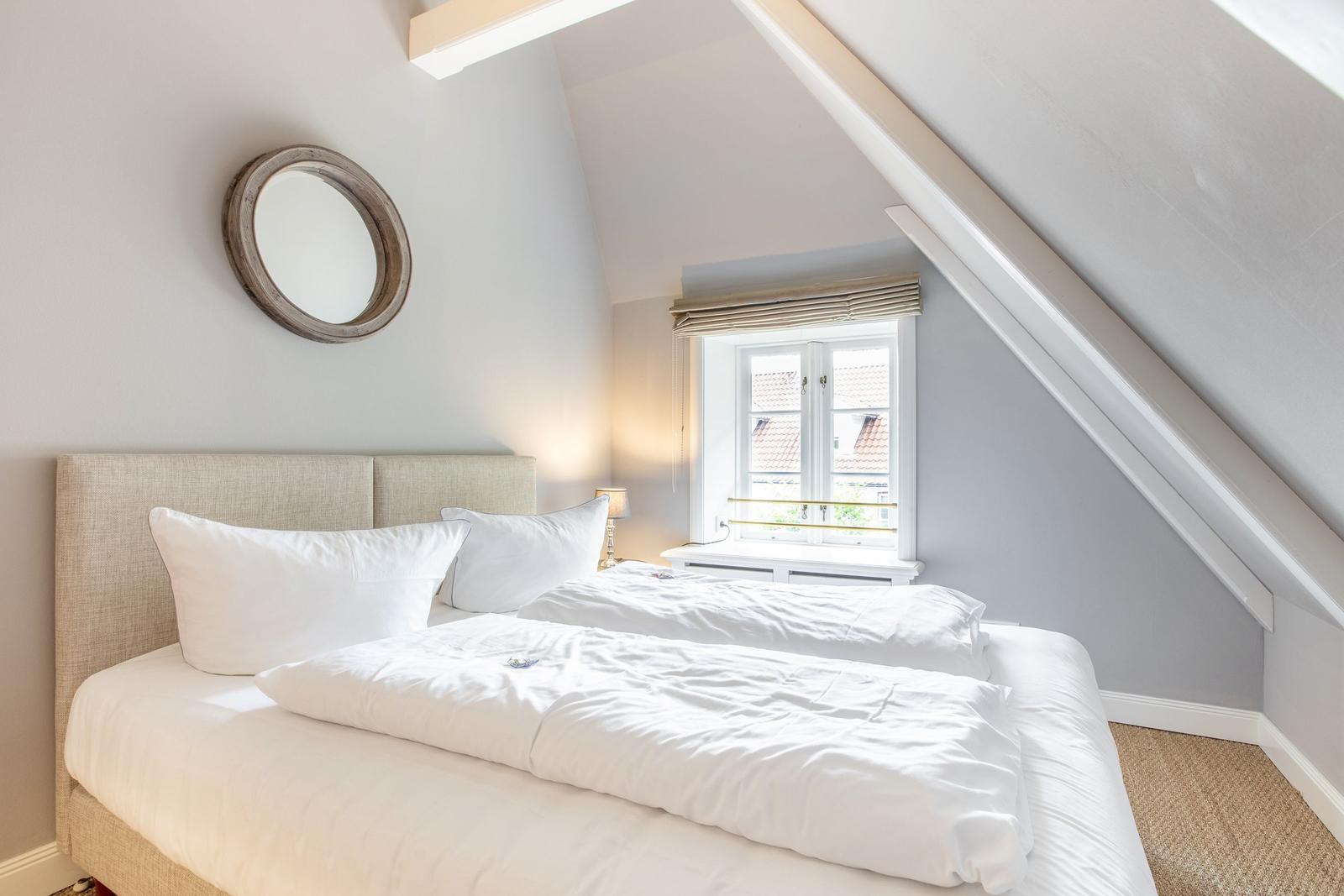 Bedroom with sloped ceiling, bed, and window.