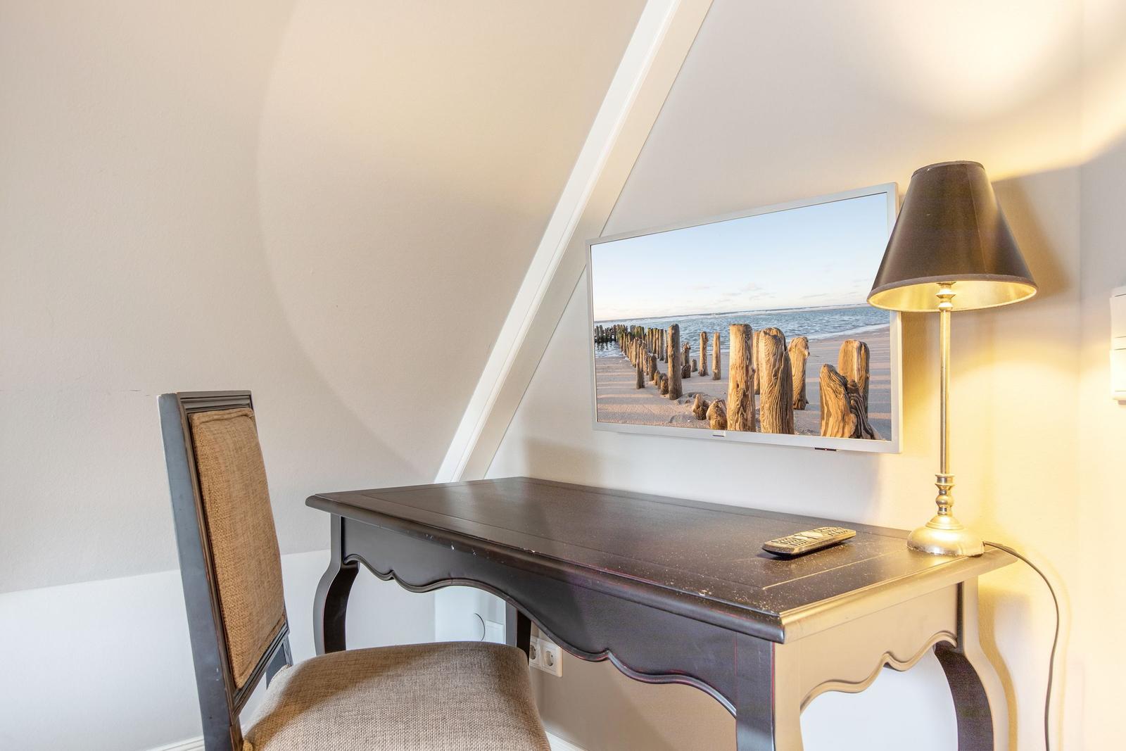 Desk with chair and TV on slanted wall.