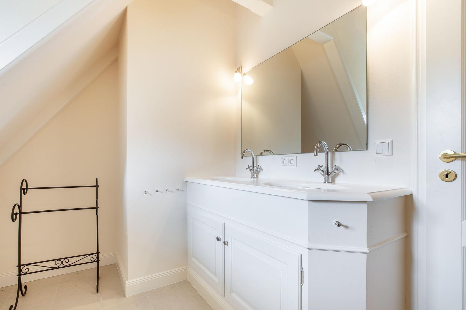 Bathroom with sink, mirror, and towel rack under sloped ceiling