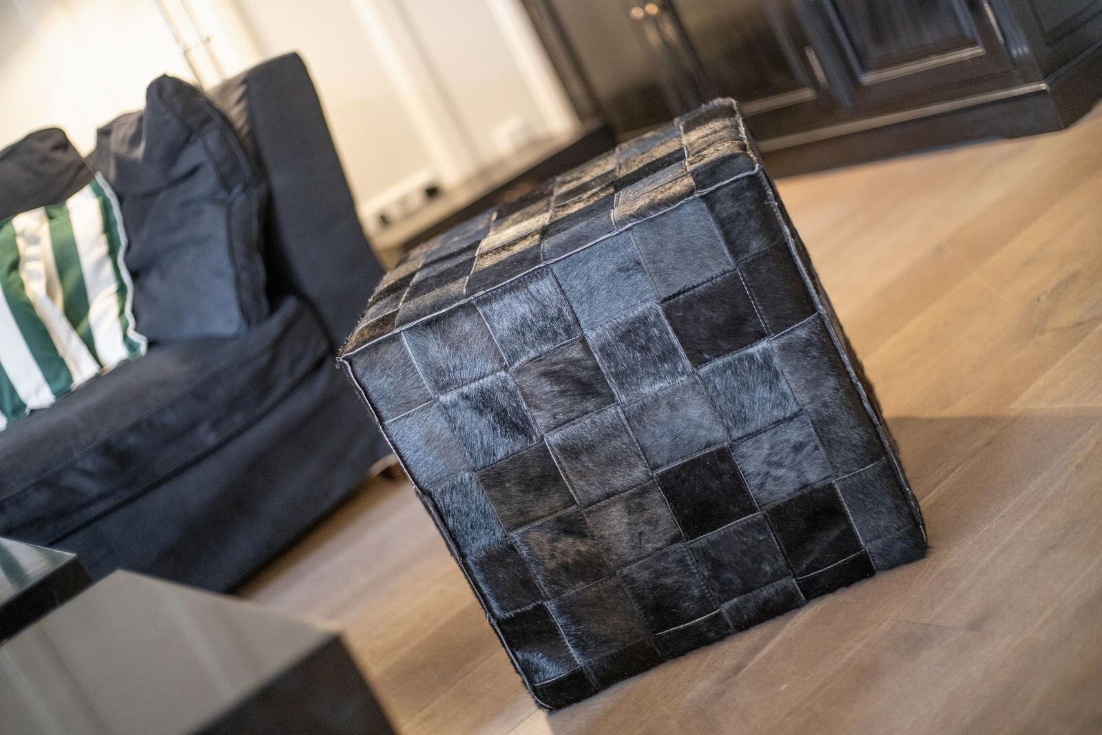 Black cowhide ottoman with cushions on wooden floor
