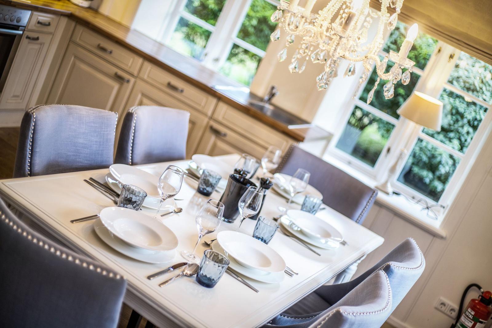 Dining room with set table, chandelier, and windows to the garden