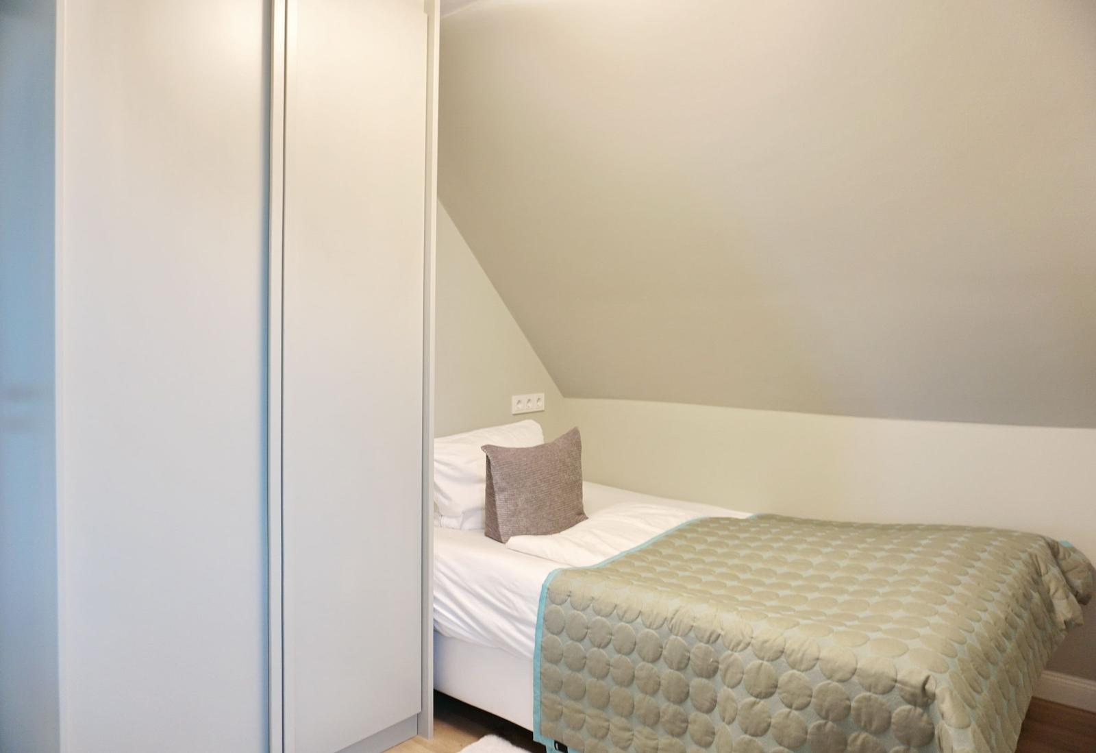 Schlafzimmer mit Dachschräge, Bett und Kleiderschrank.