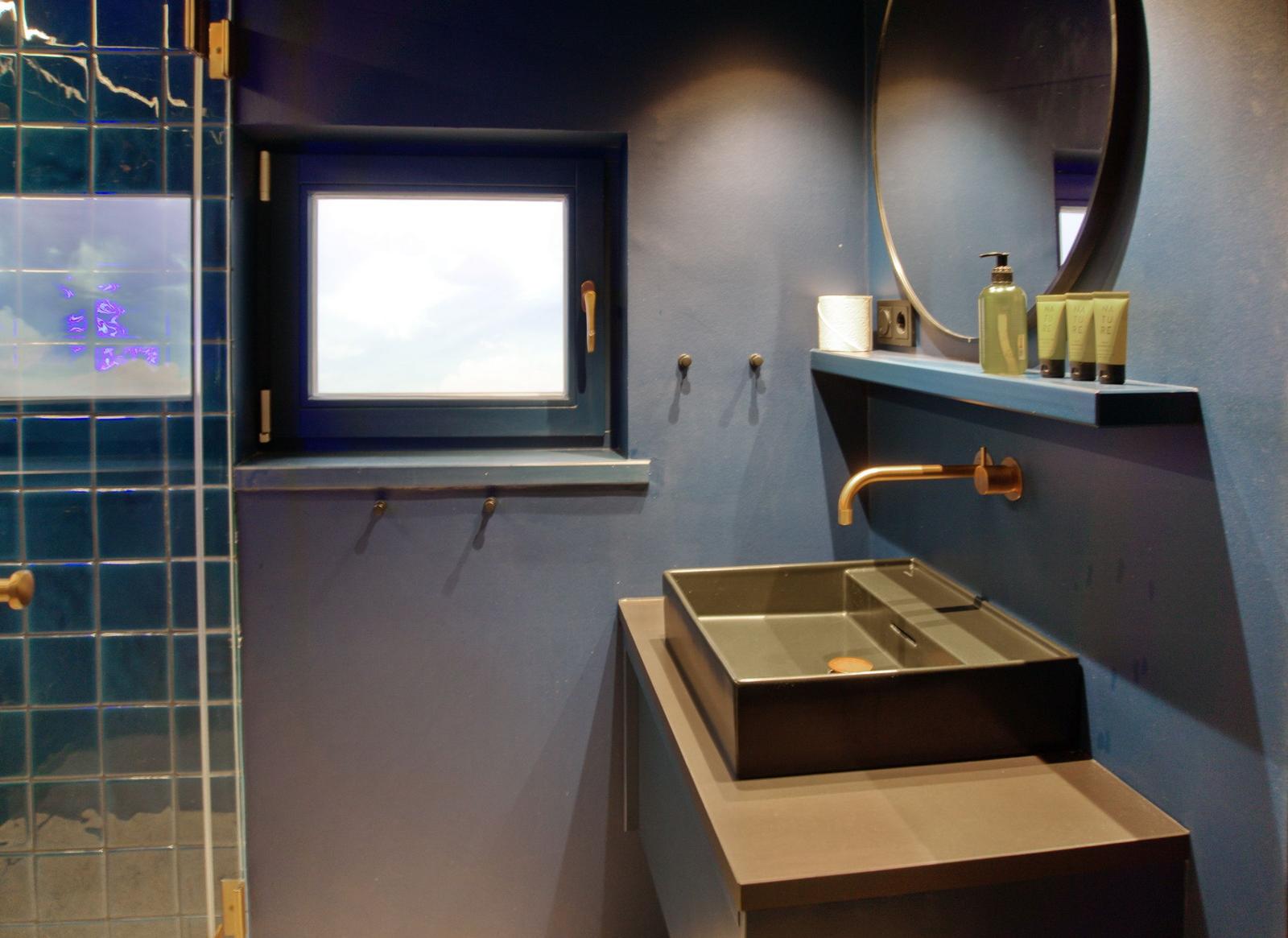 Badezimmer mit blauen Wänden, Waschbecken und Duschbereich.