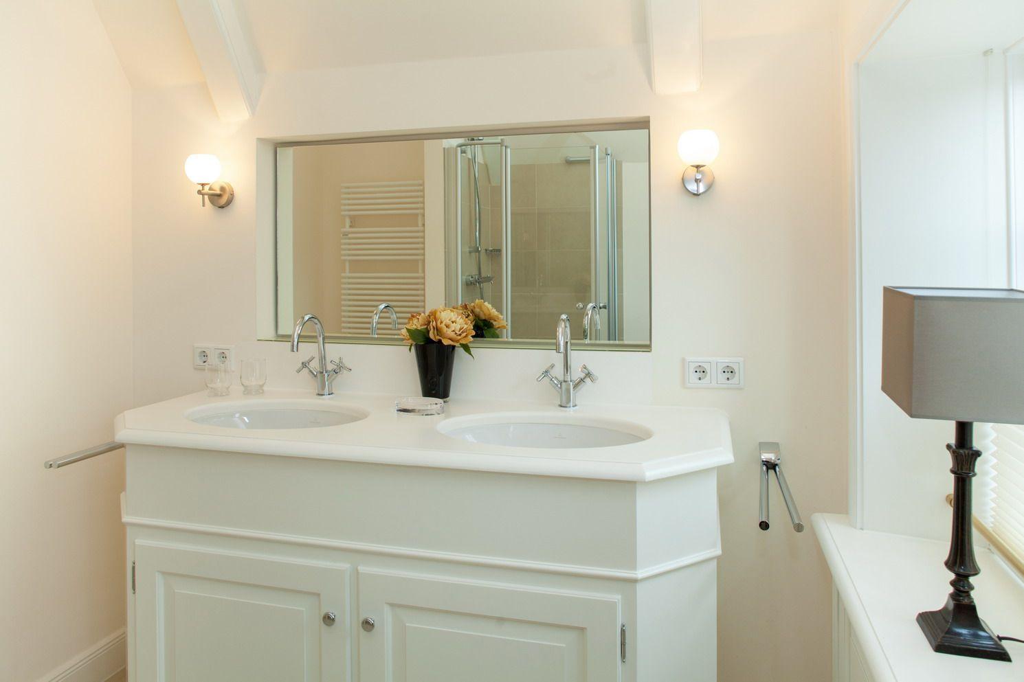 Doppelwaschbecken mit Spiegel und Dusche im Badezimmer.