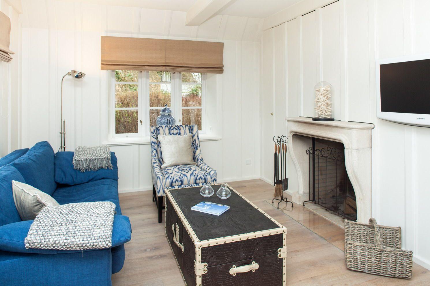 Wohnzimmer mit blauem Sofa, Kamin und Holzboden.