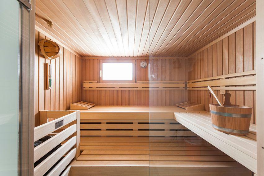 Wooden sauna with benches, bucket, and small window.