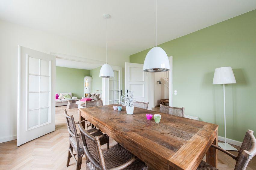 Dining area with wooden table and chairs, green wall and white ceiling