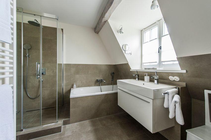 Bathroom with shower, bathtub, and sink under sloped ceiling.