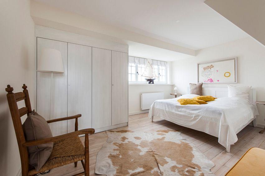 Bedroom with bed, wardrobe, and wooden chair on cowhide rug.