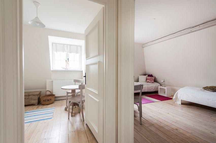 Room with wooden floor, bed, table and chairs. Window with curtain.