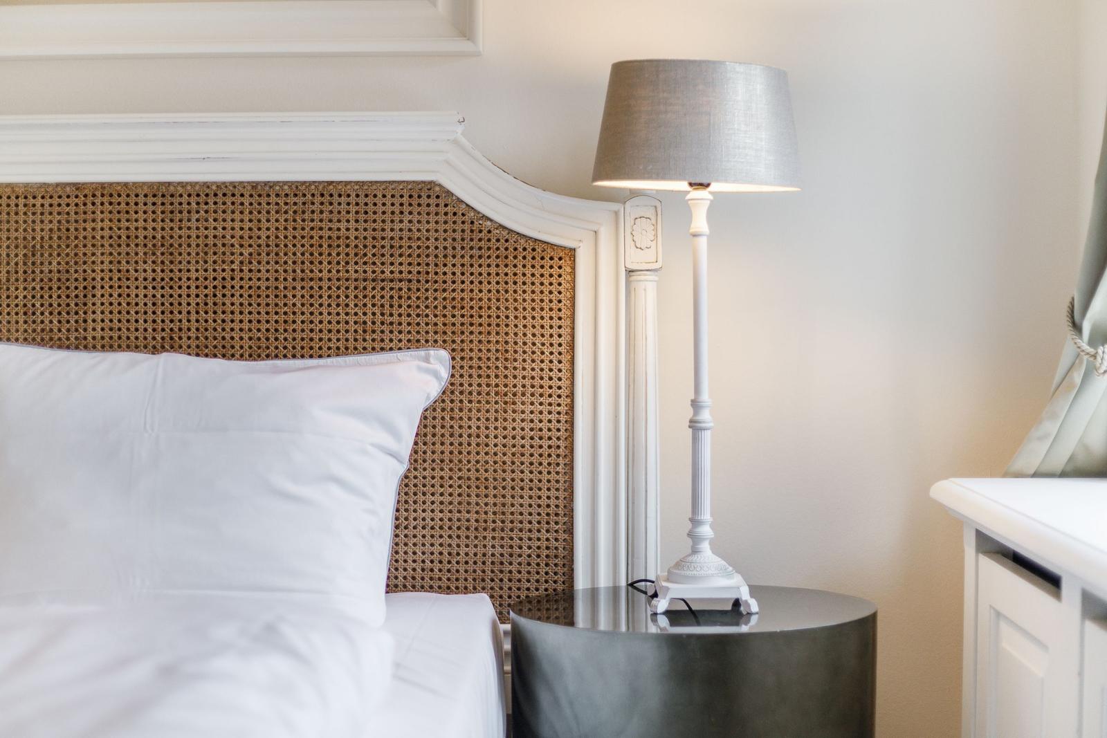 Schlafzimmer mit Bett, Nachttisch und Stehlampe.