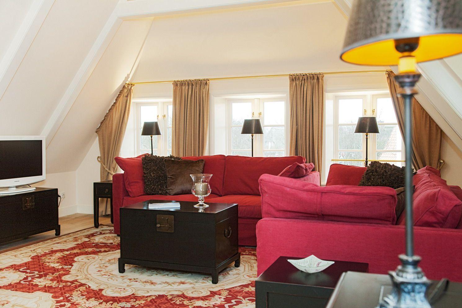 Living room with red sofa, rug, and windows.