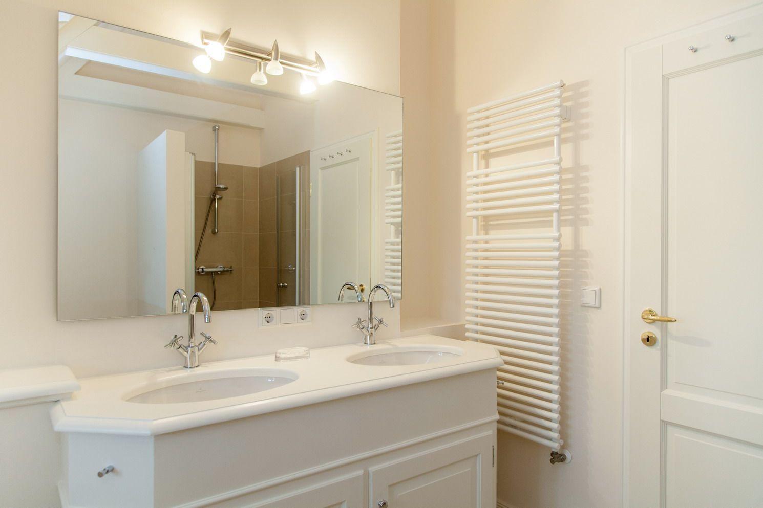 Bathroom with double sink, mirror, and radiator