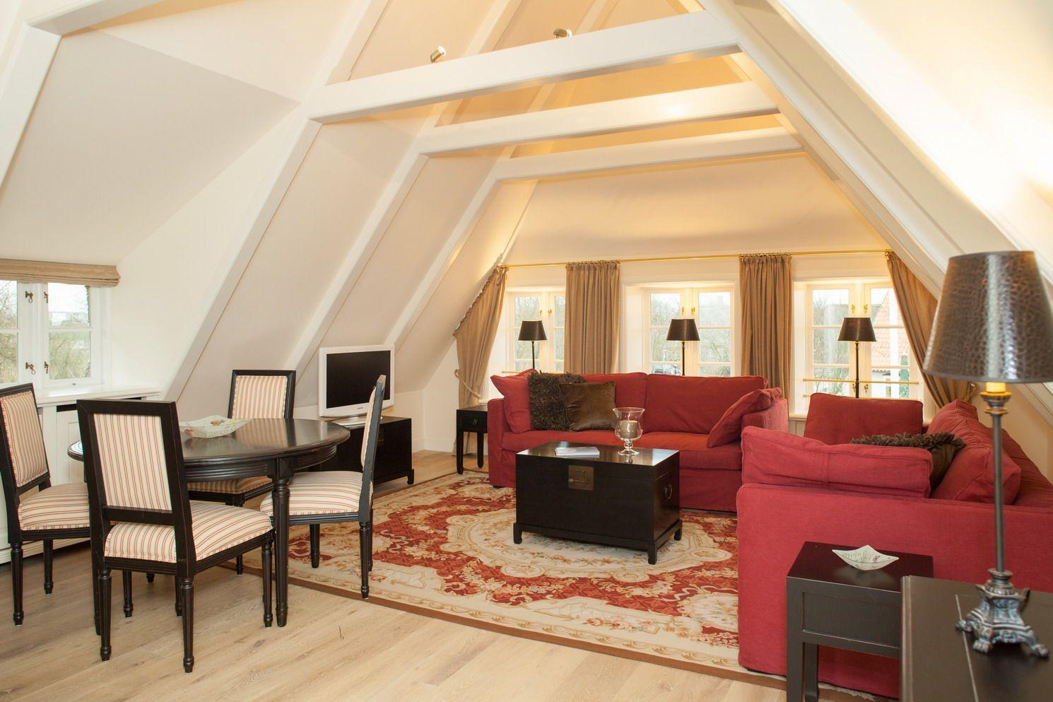 Living and dining area with red sofa, table and chairs under sloped ceilings.