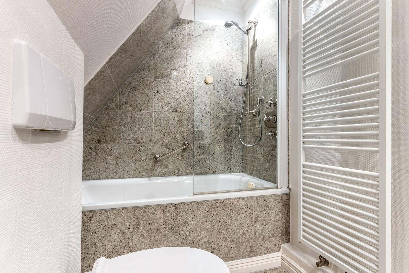 Badezimmer mit Dusche, Badewanne und Heizkörper