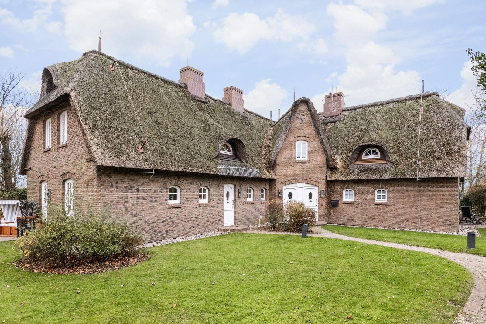 Dorfhaus mit strohgedecktem Dach und gemauertem Außenbereich.