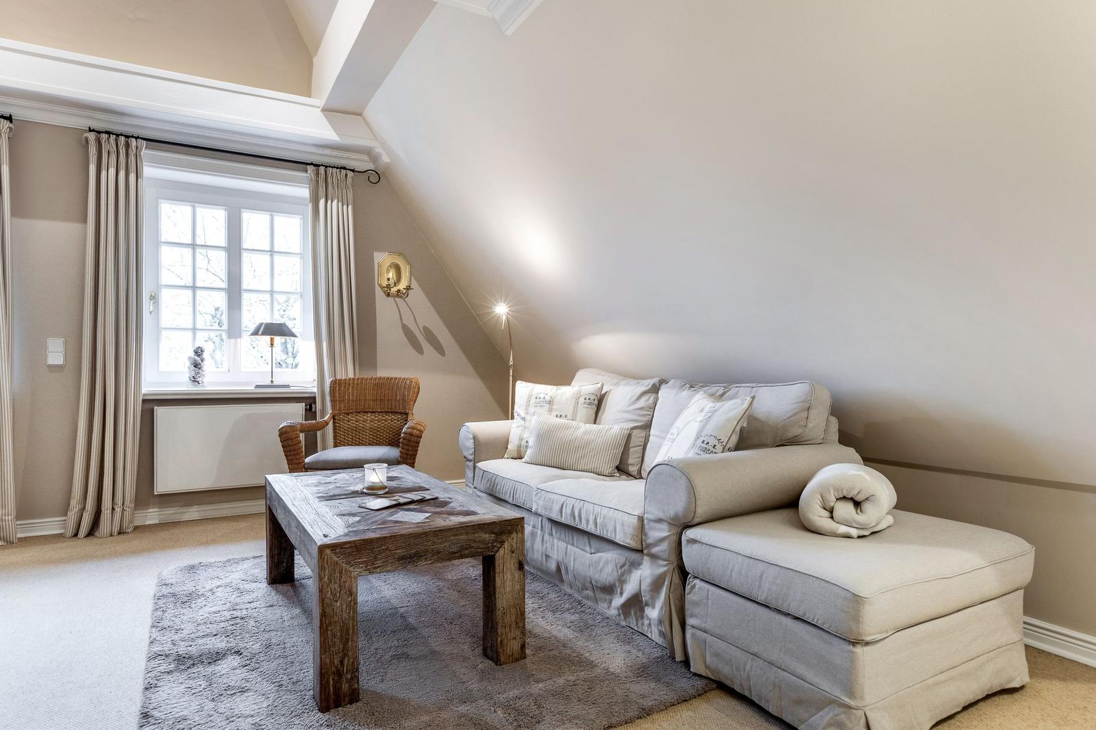 Wohnzimmer mit Sofa, Couchtisch und Fenster mit Vorhängen.