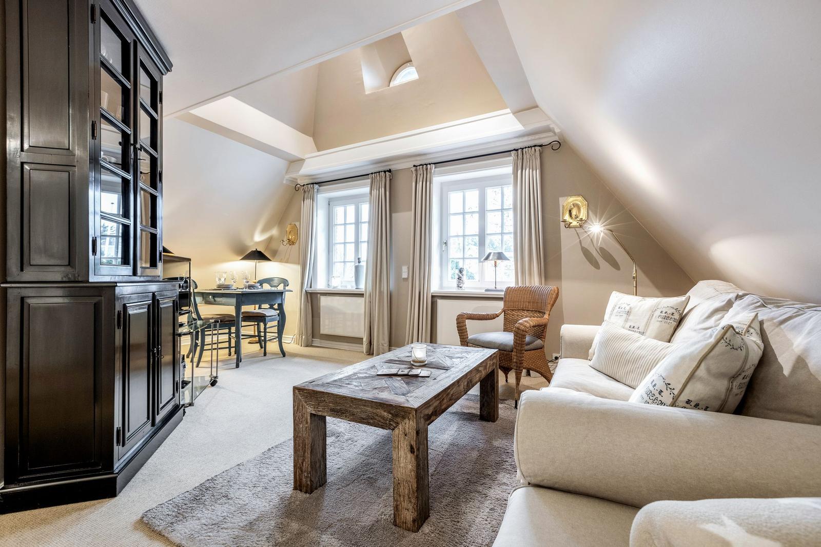 Wohnzimmer mit Sofa, Couchtisch und Essbereich unter Dachschrägen.