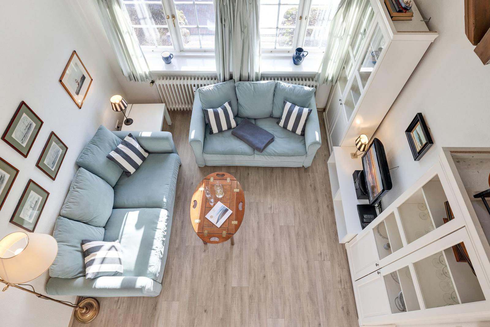 Wohnzimmer mit hellblauen Sofas, Holztisch und weißen Schränken.