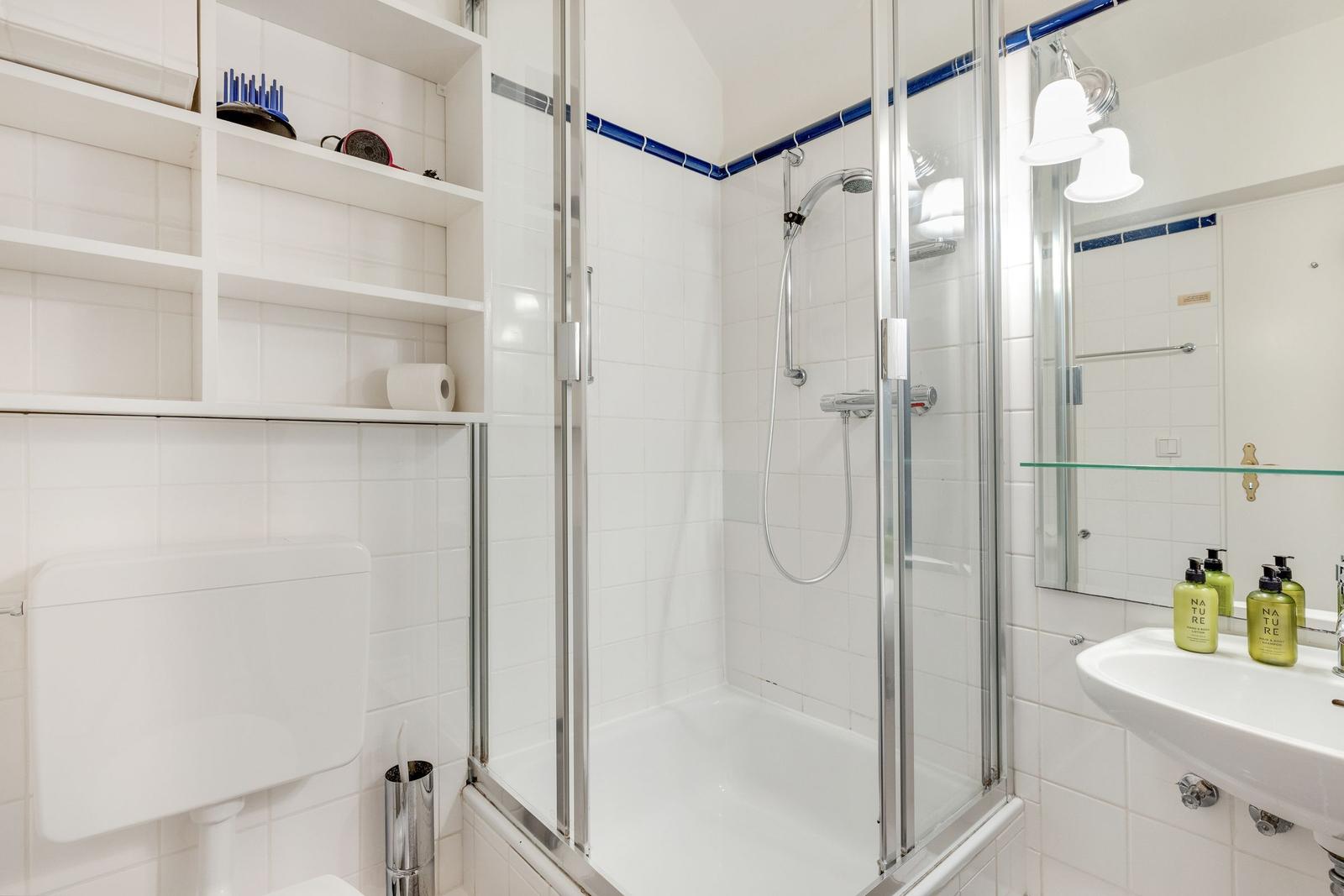Badezimmer mit Dusche, Waschbecken und Regal