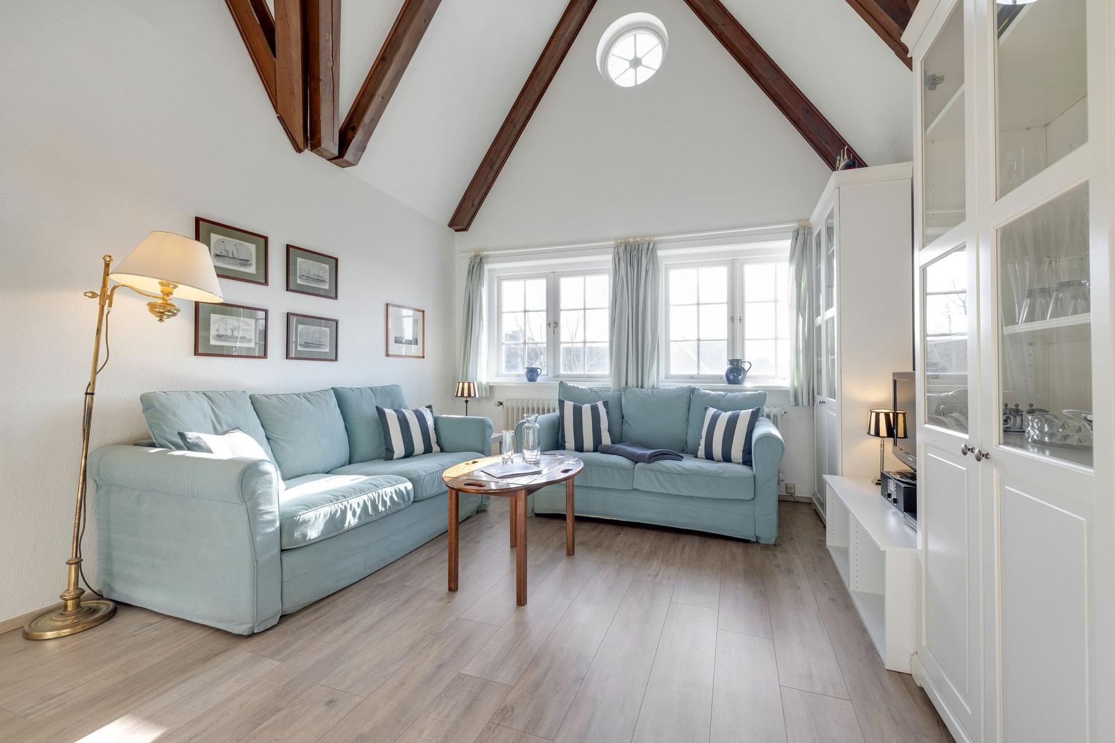 Wohnzimmer mit zwei hellblauen Sofas, Holzboden und hohen Deckenbalken.