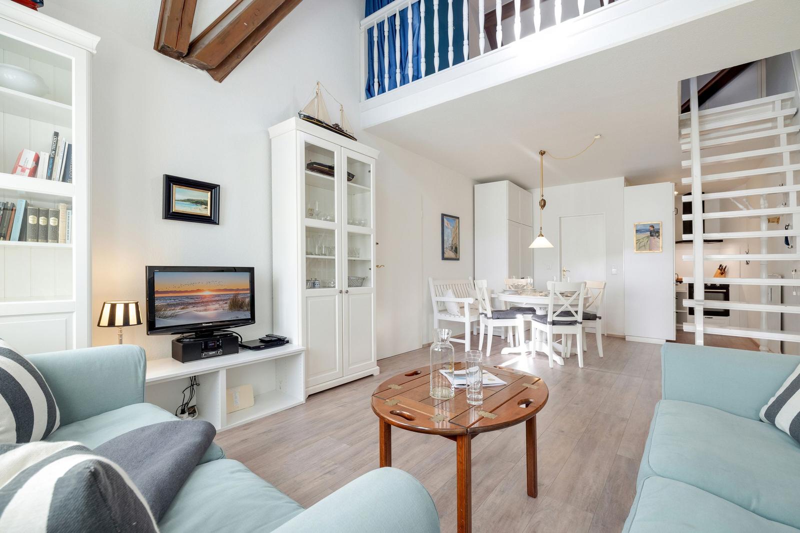 Wohn- und Essbereich mit Holztisch, Sofa und Treppenaufgang zur oberen Etage.