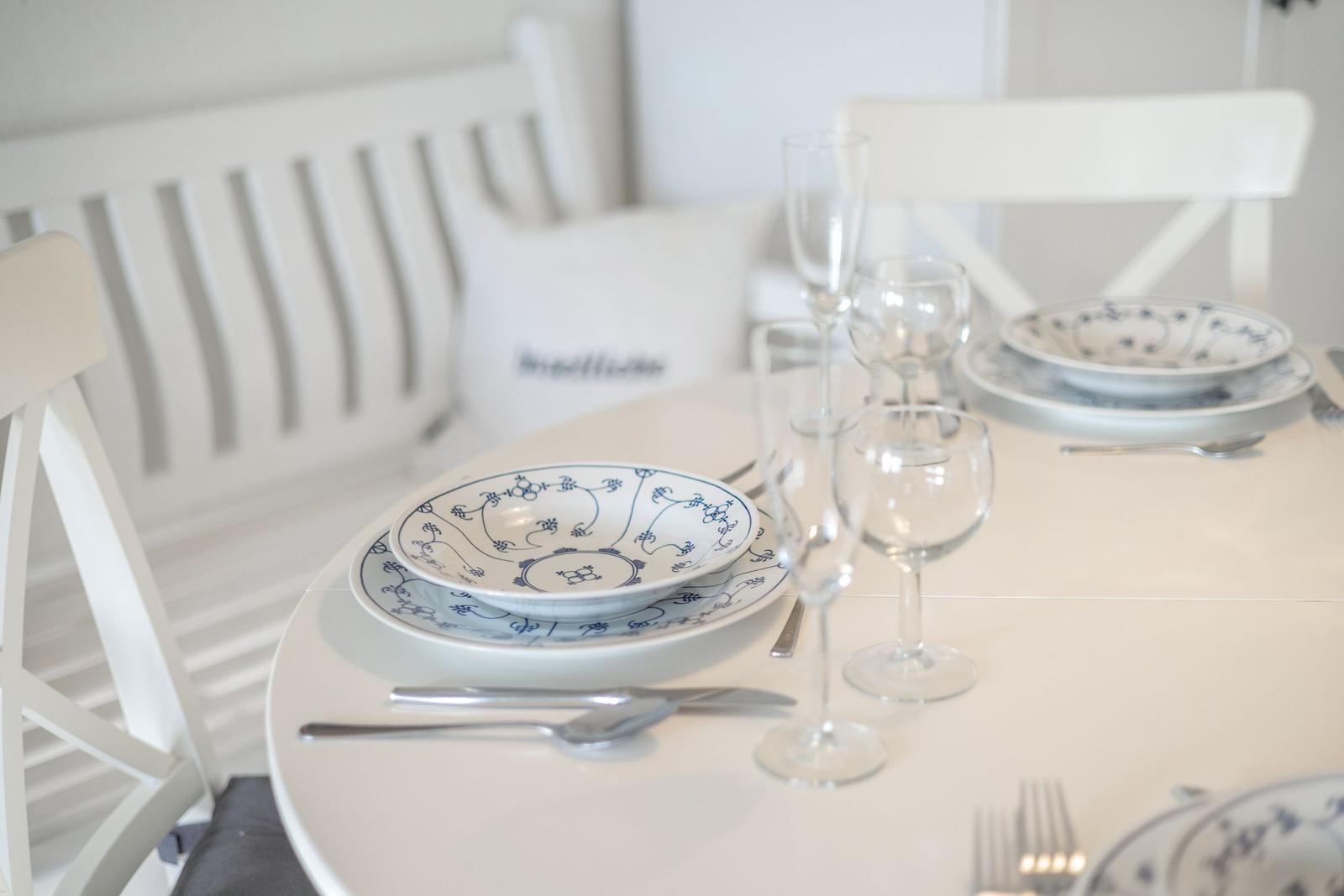 Runder Tisch mit weißen Stühlen und blau-weißen Teller Sets.
