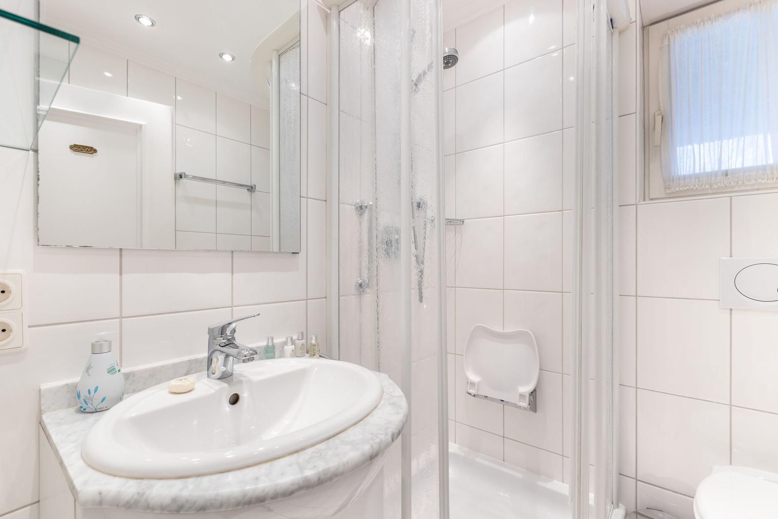 Badezimmer mit Dusche, Waschbecken und Spiegel.