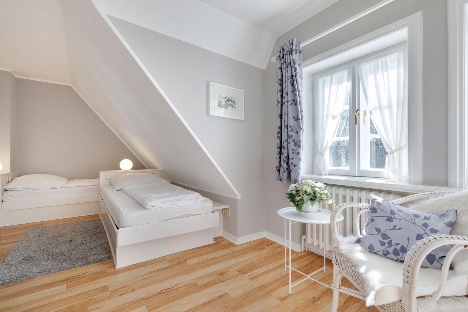 Room with two beds, window, chair, and flowers