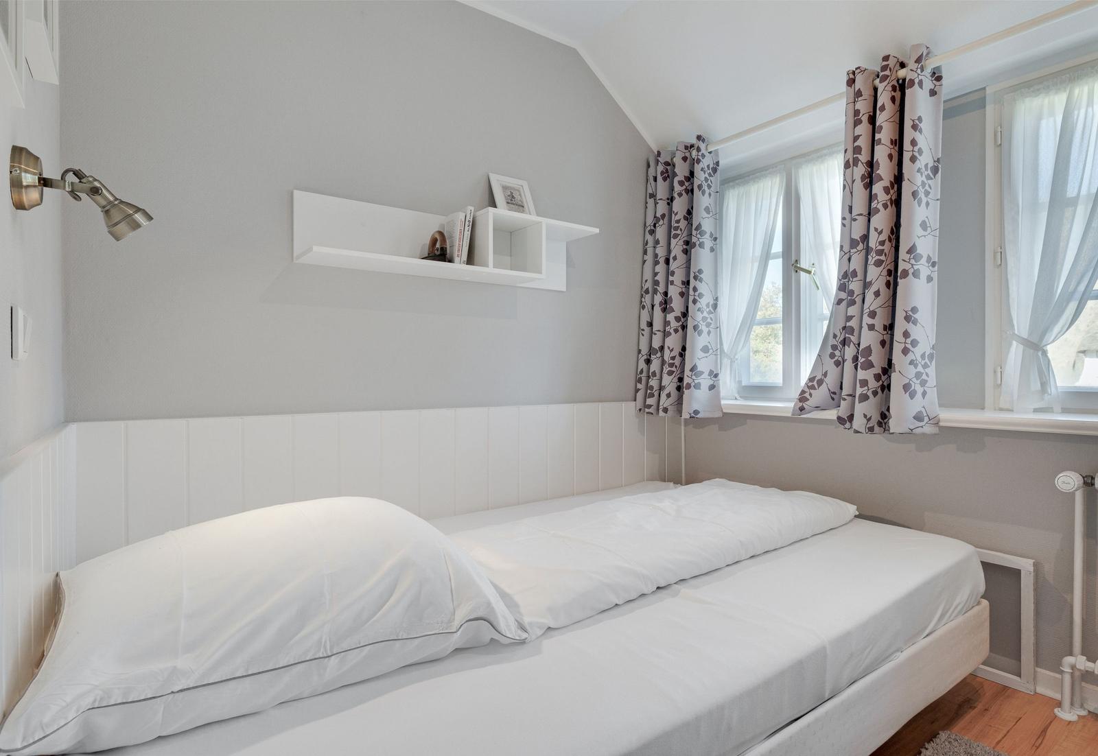 Bedroom with bed, window, and wall shelf.