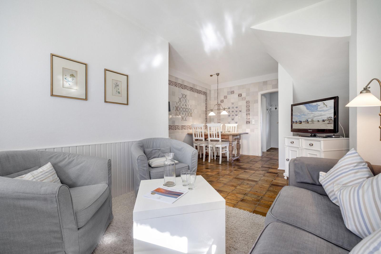Living and dining area with gray sofas, white coffee table, and wooden floor.