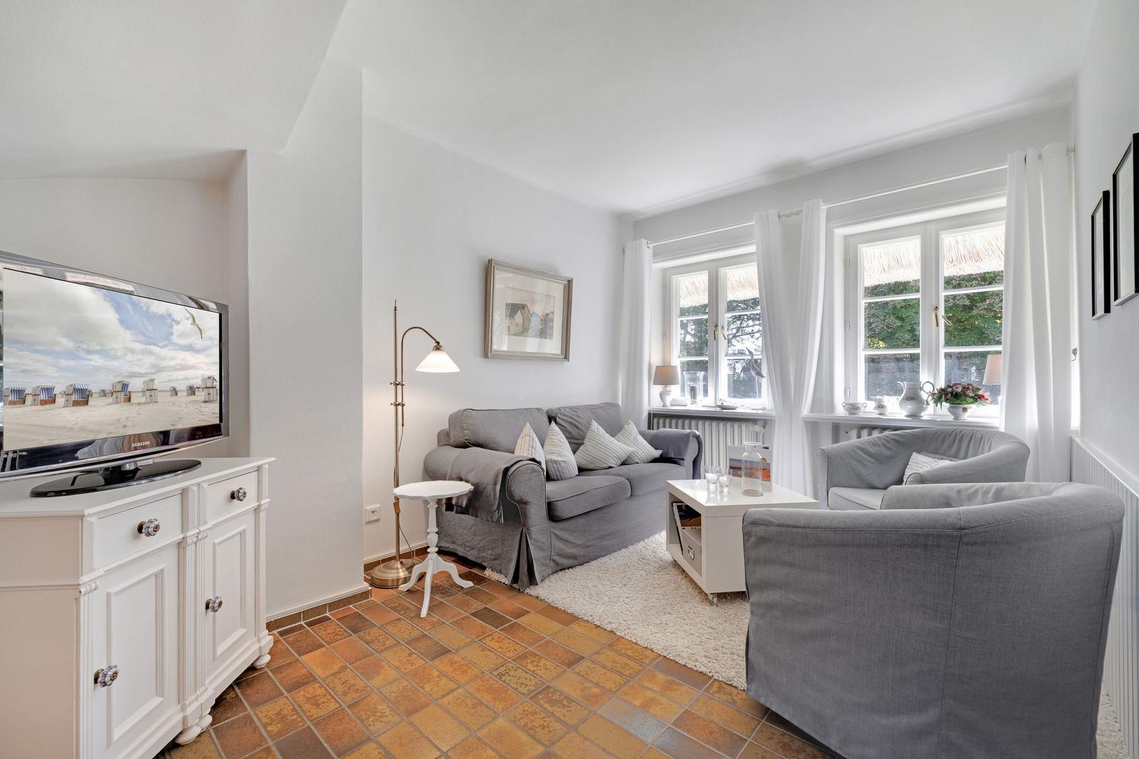 Living room with sofa, armchairs, TV, and windows.