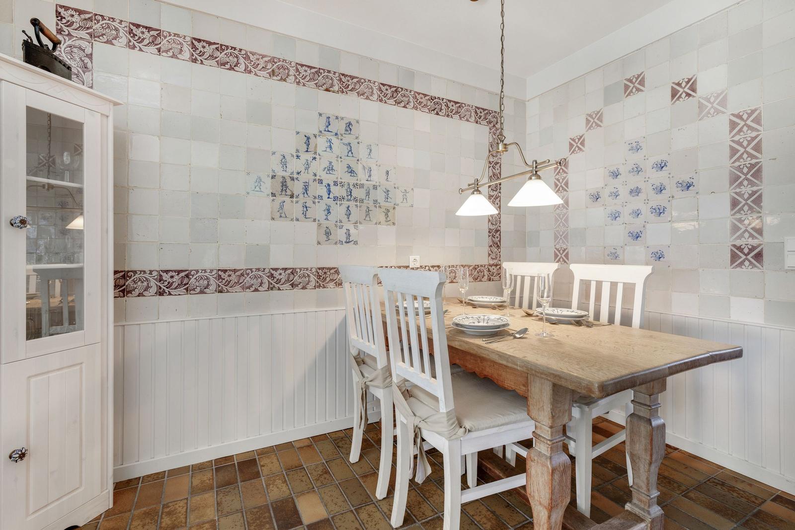 Dining room with wooden table, white chairs, and tiled walls.