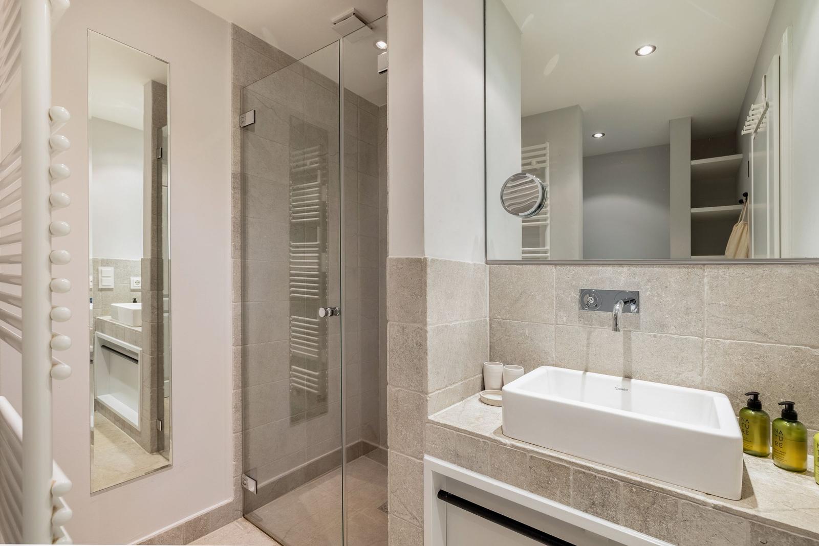Badezimmer mit Dusche, Waschbecken und Spiegel