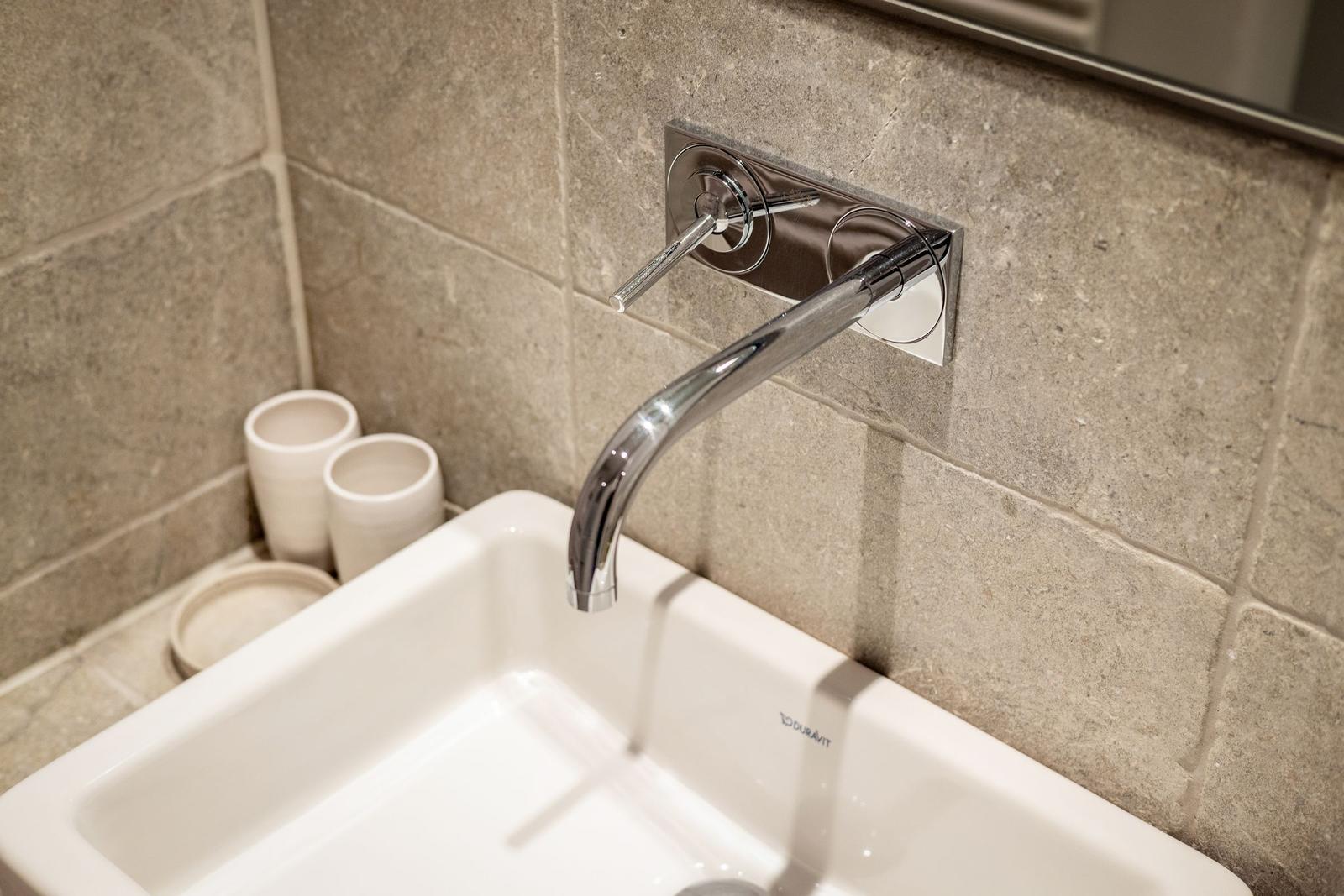 Hochwertige Waschbecken mit modernem Wasserhahn und grauen Fliesen.