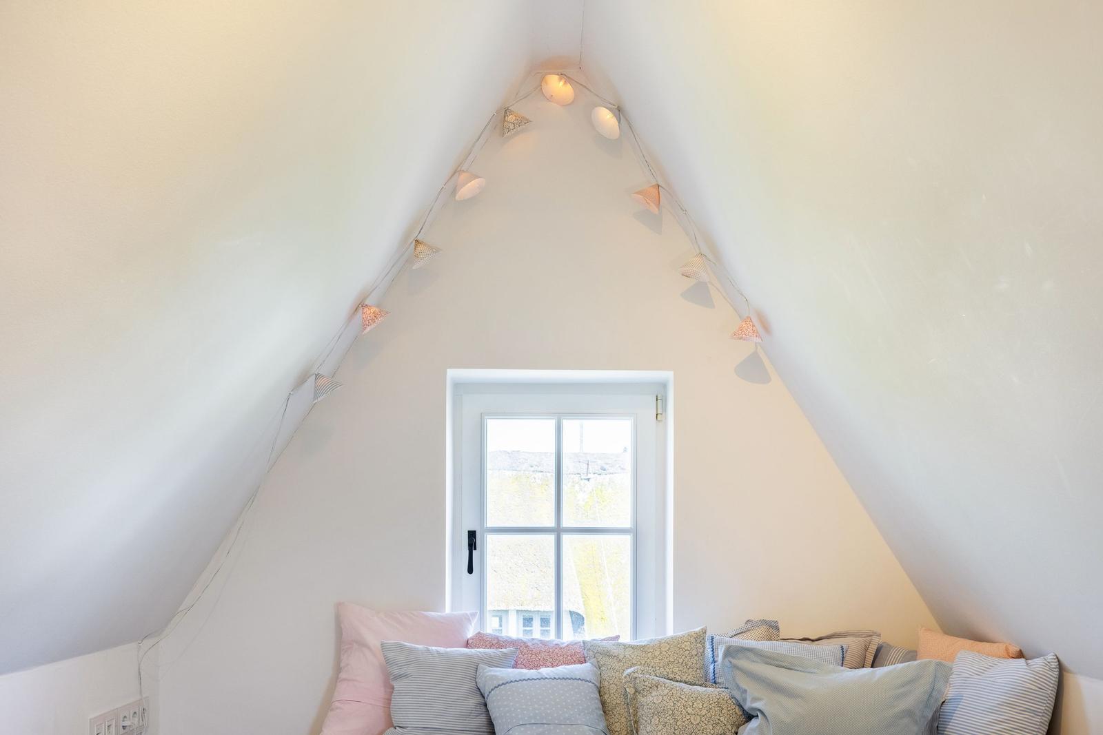 Schlafzimmer mit Dachschrägen, Fenster und Kissen