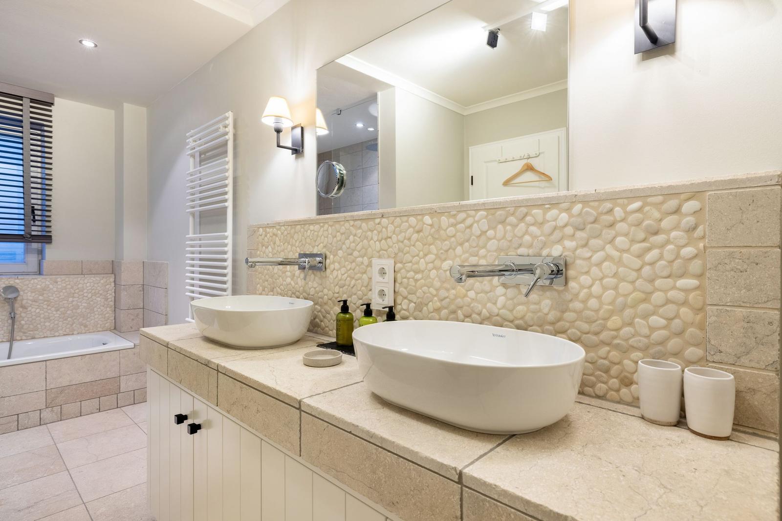 Badezimmer mit zwei Waschbecken, Steinwand und Badewanne.