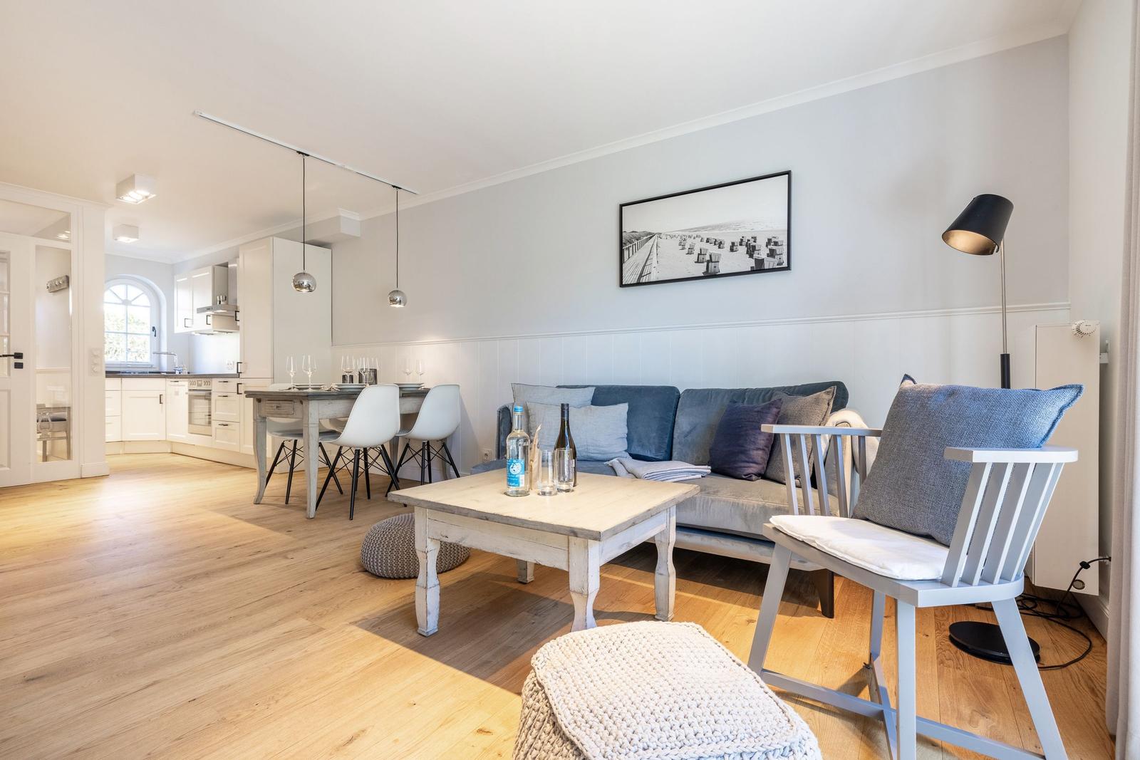 Wohn- und Essbereich mit Sofa, Tisch und Stühlen. Küche im Hintergrund.