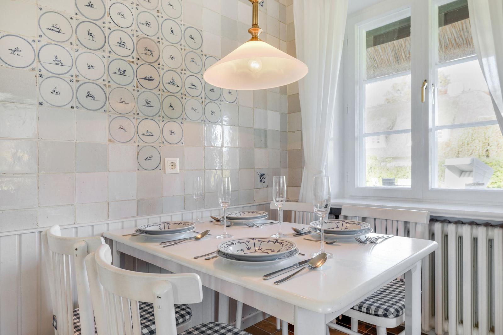 Dining room with white table, chairs, and decorative tiles on the wall.