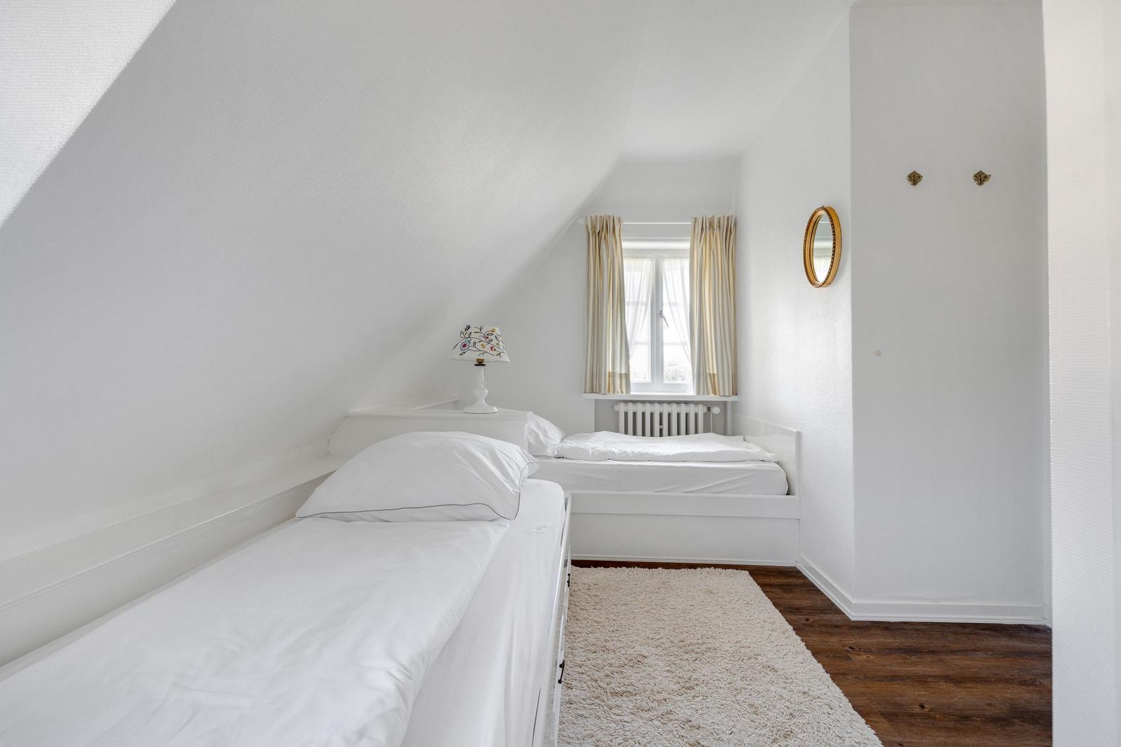 Room with two beds, window, and mirror on the wall.