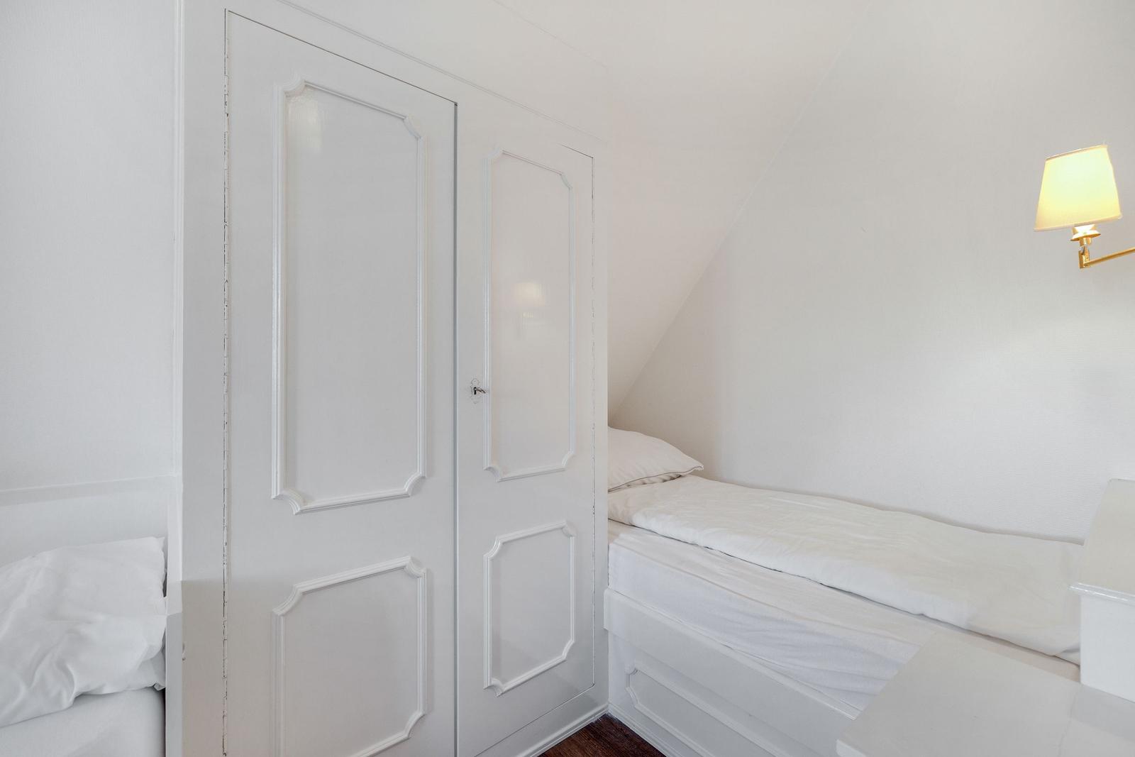 Bedroom with double bed, white closet, and wall lamp