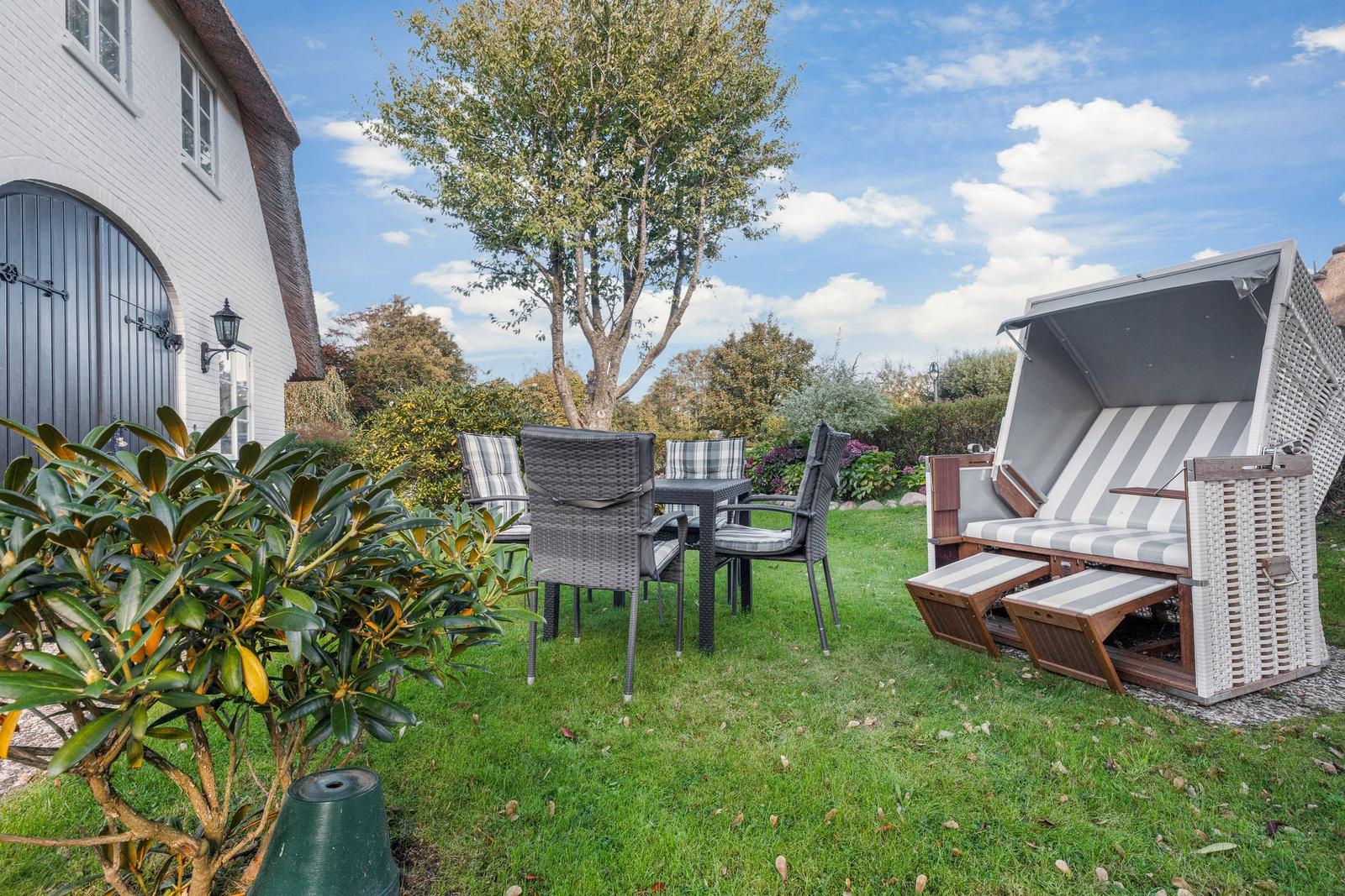 Garden with seating group and beach chair. House with sliding door and tree.