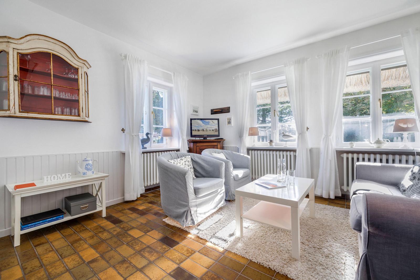Living room with gray chairs, white table, and windows with white curtains.