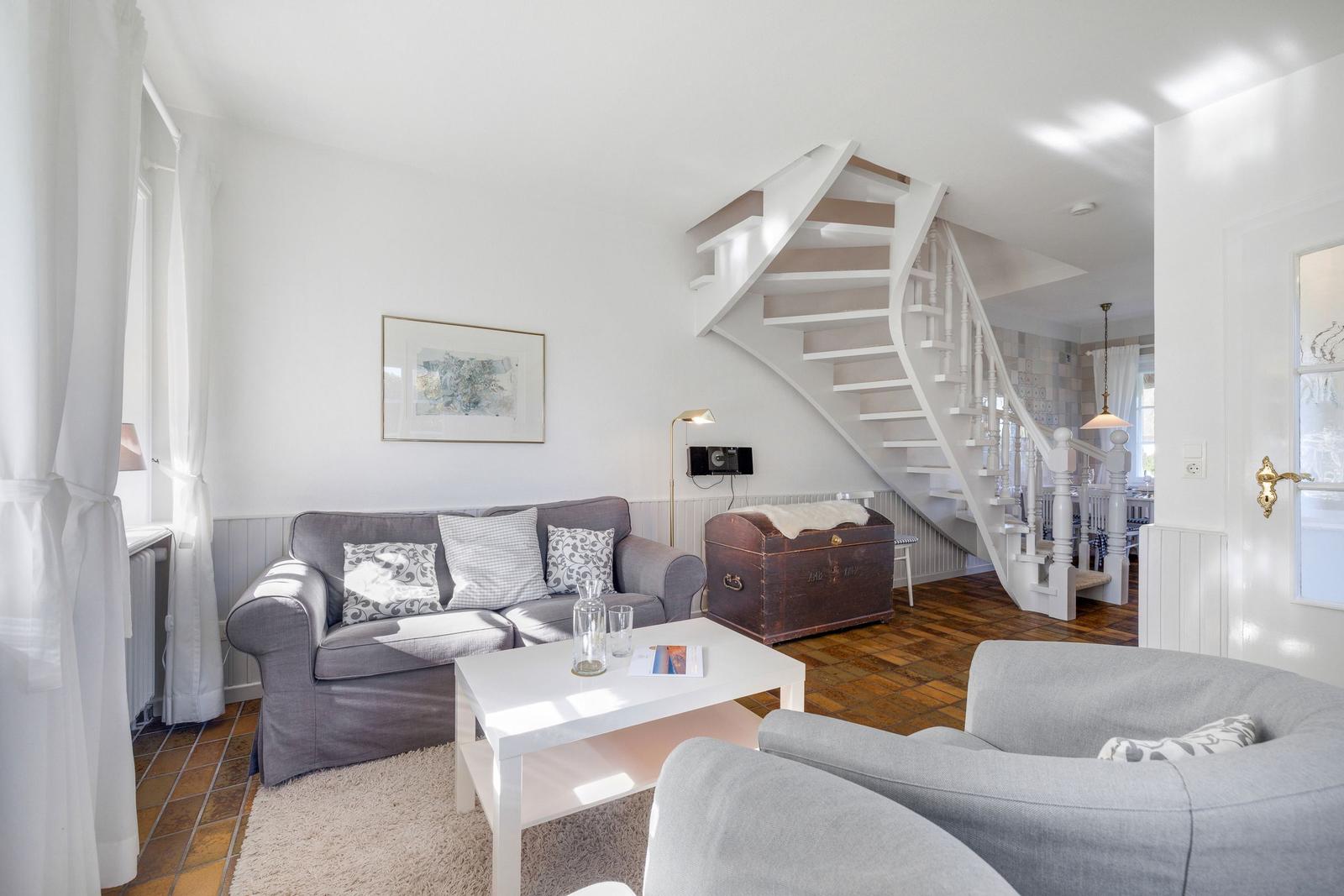 Living room with gray sofa, white table, and spiral staircase.