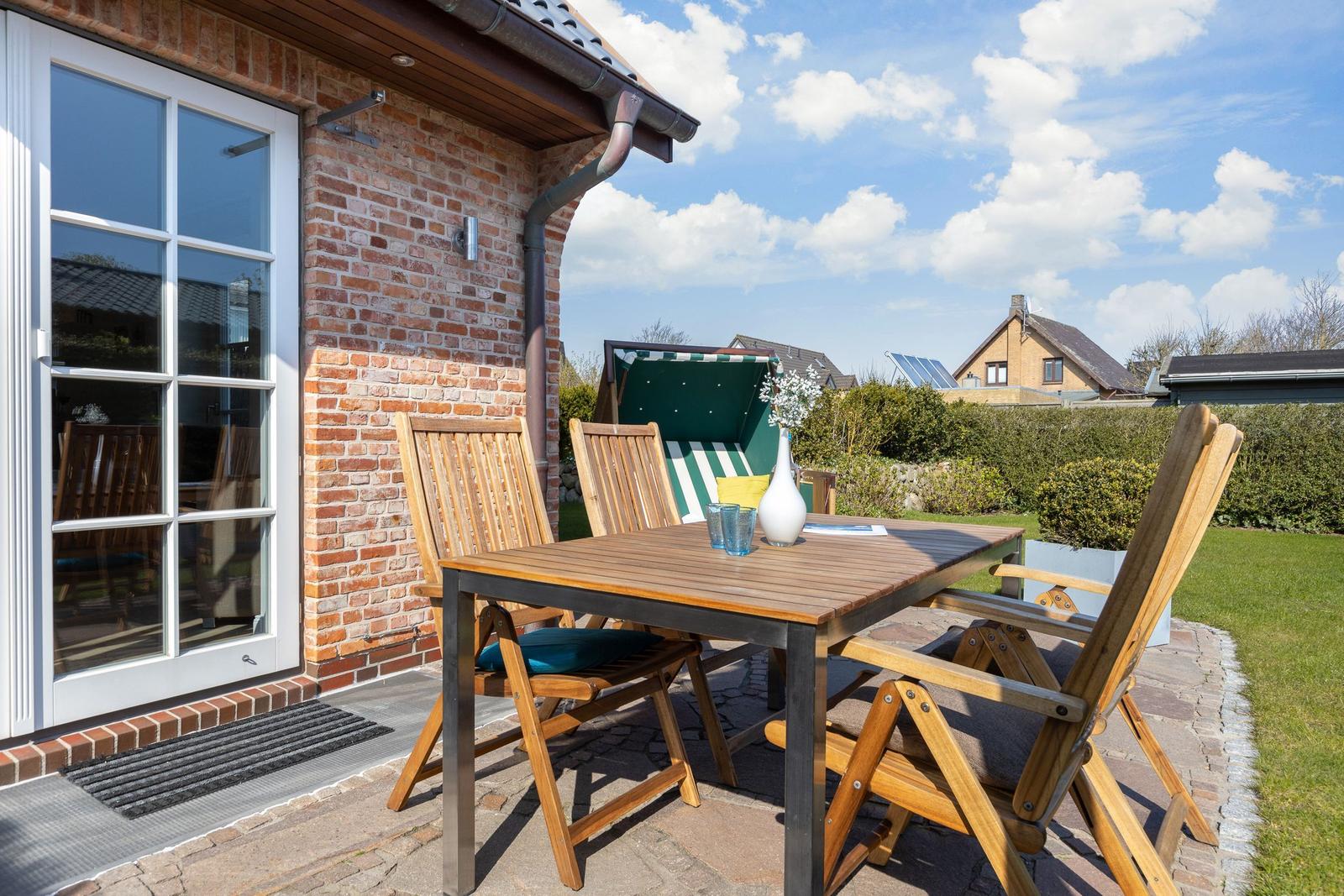 Terrasse mit Holztisch und Stühlen, grüner Hinterhof und Sitzmöbel