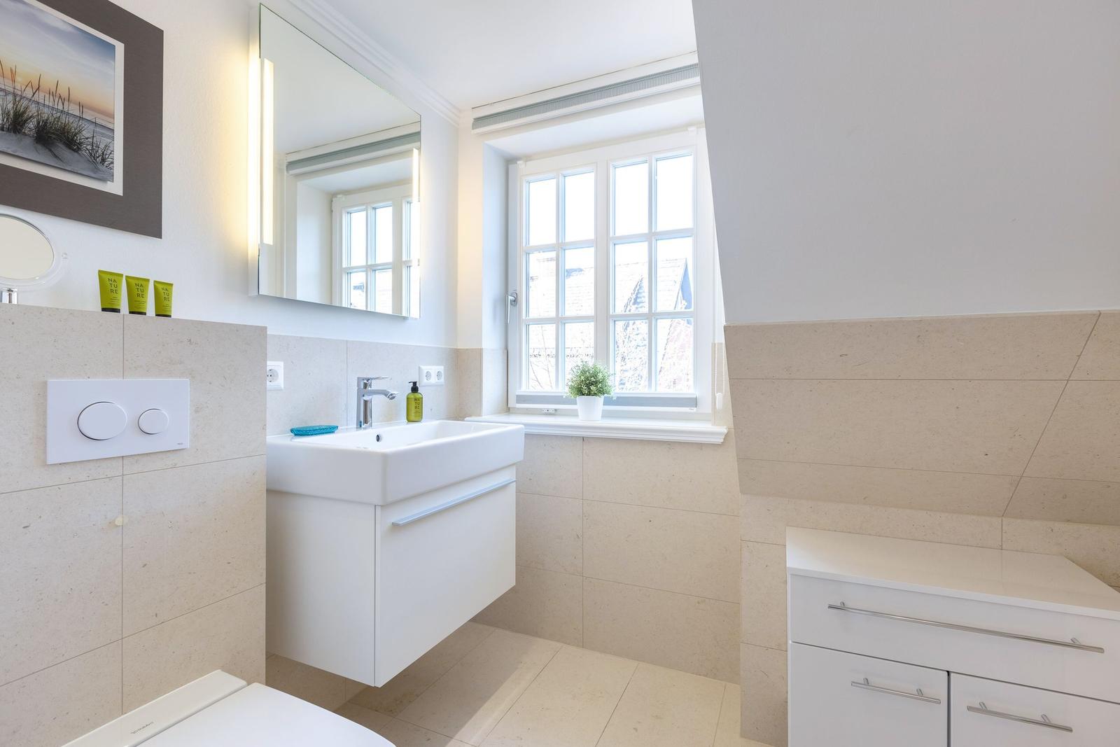 Badezimmer mit Waschbecken, Spiegel und Fenster