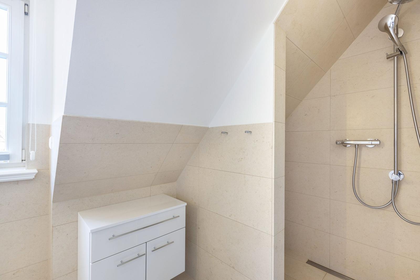 Badezimmer mit Dusche, Waschbecken und Fenster