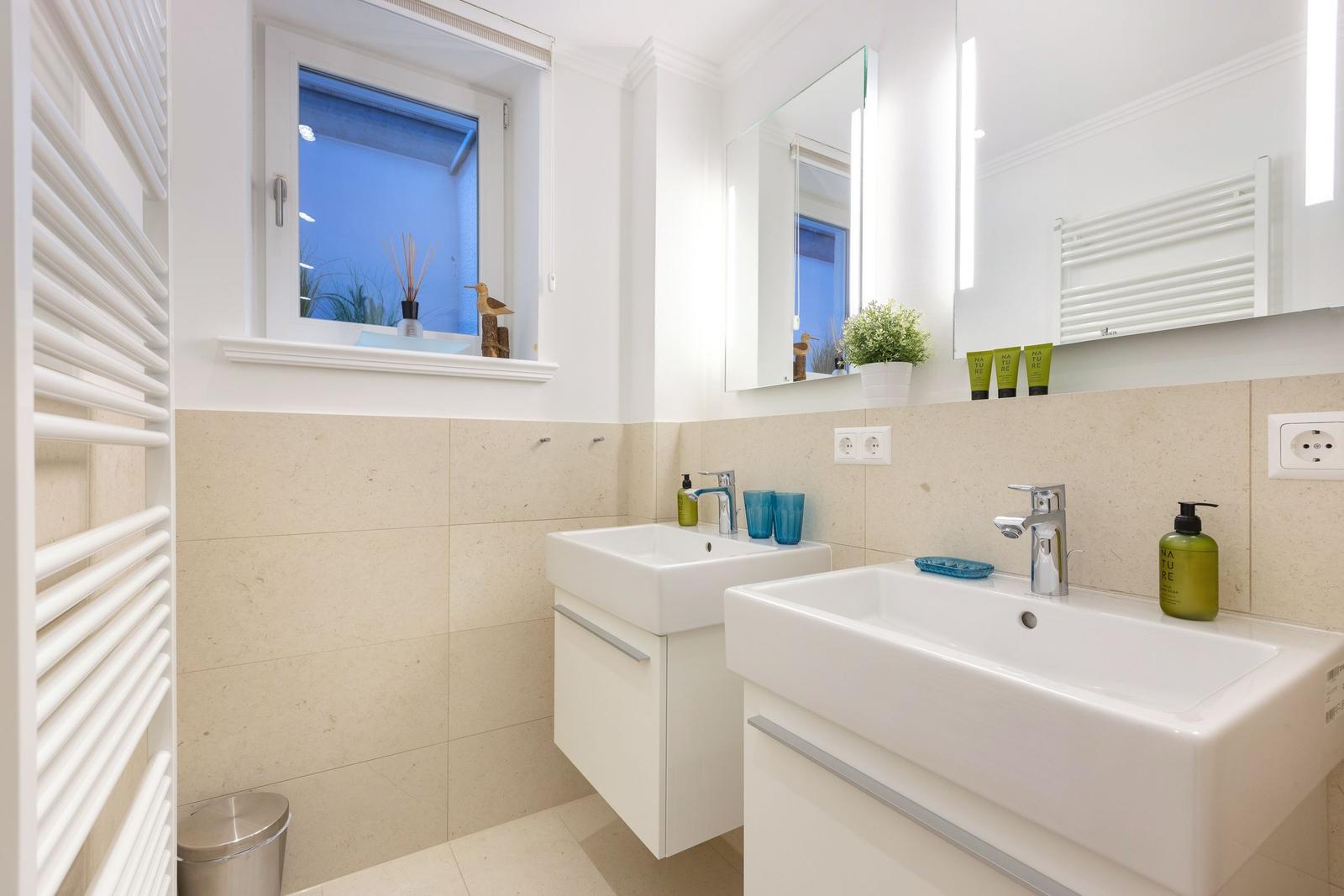 Zwei Waschbecken mit Spiegeln und Fenster im Badezimmer.