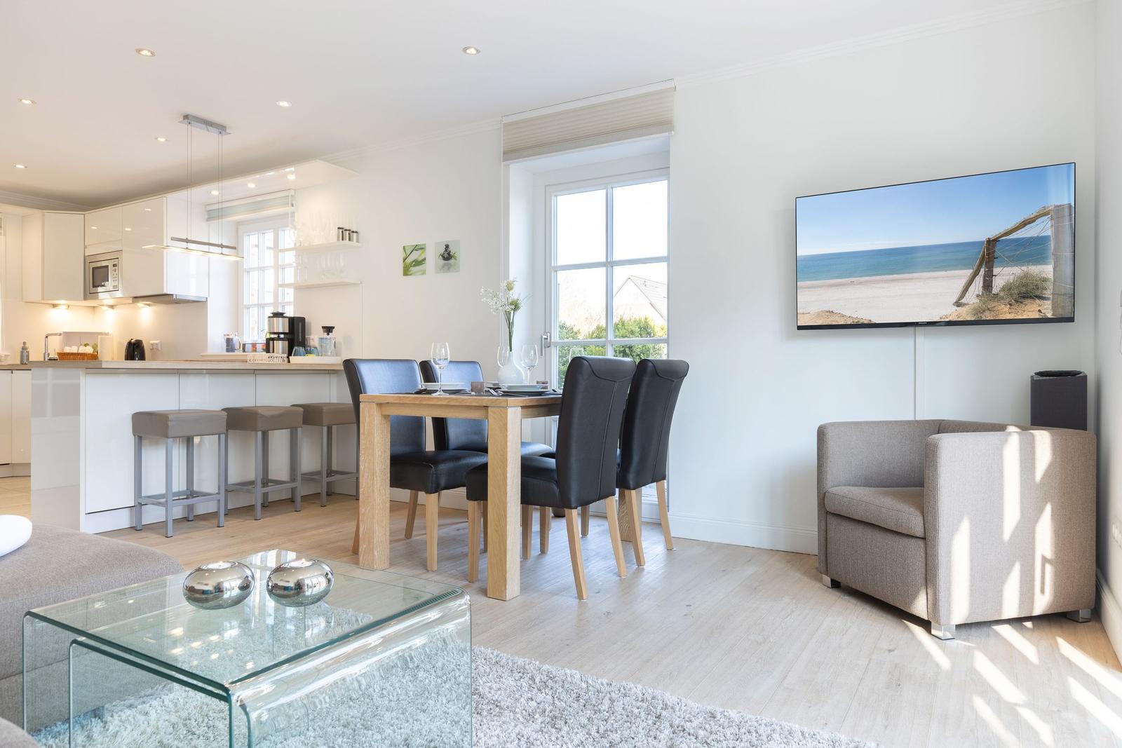 Moderne Küche, Essbereich und Wohnzimmer mit TV und Fenster.
