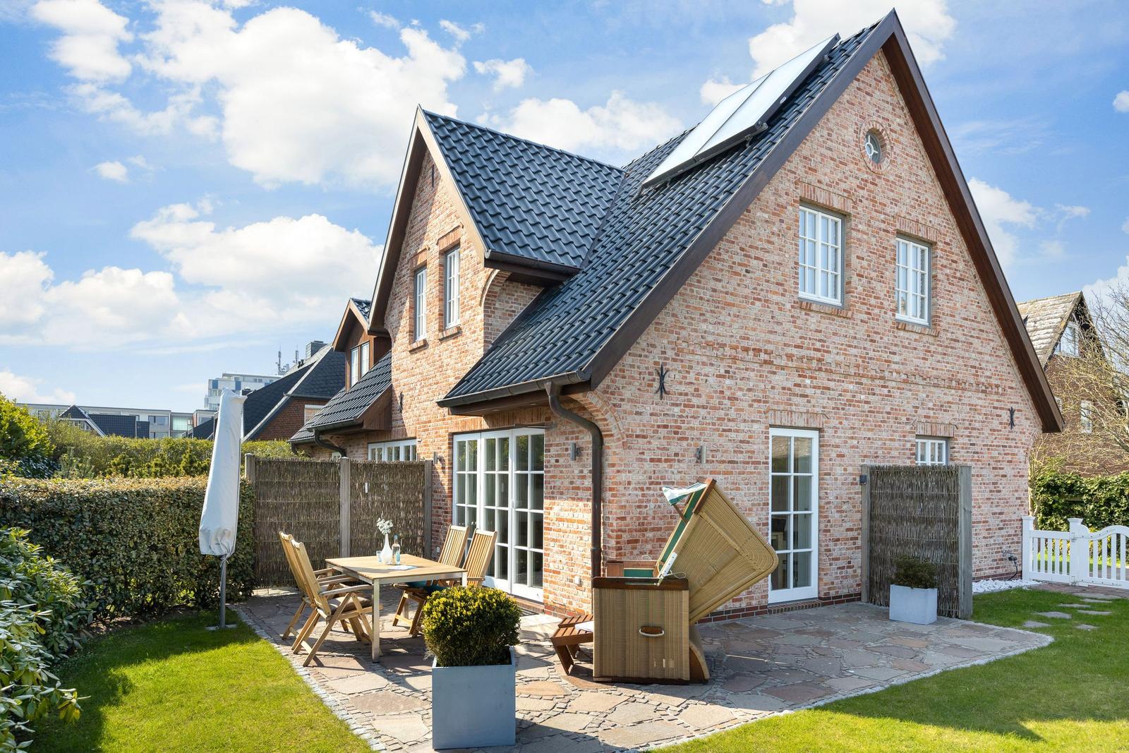 Haus mit Steinplattenhof, Holztisch, Stühlen und Whirlpool